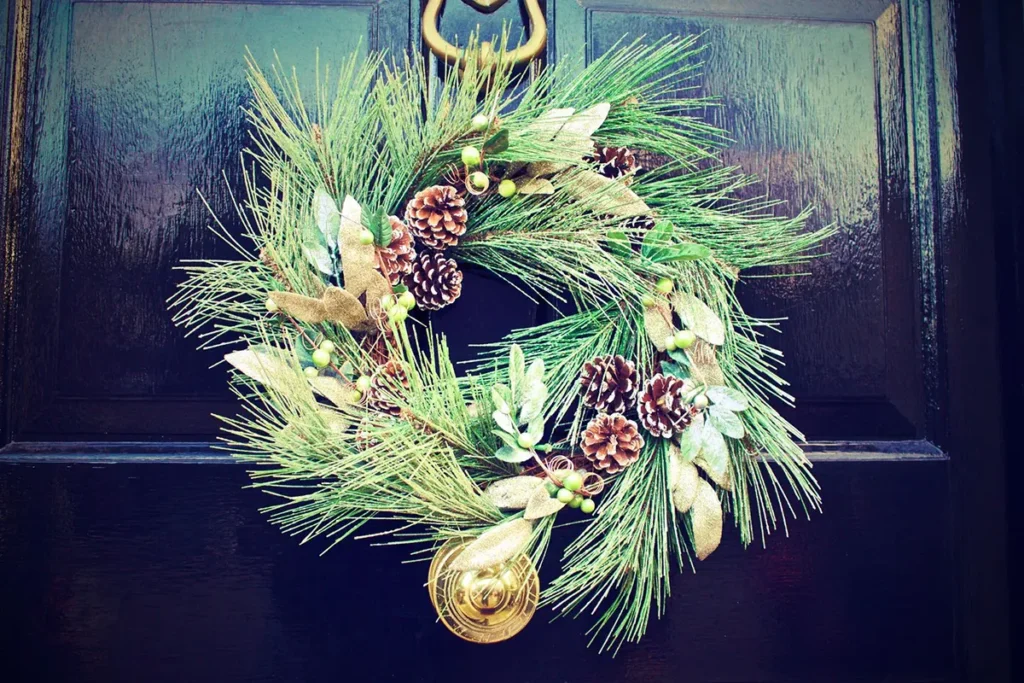 Large pine and pinecone Christmas wreath on a dark glossy front door