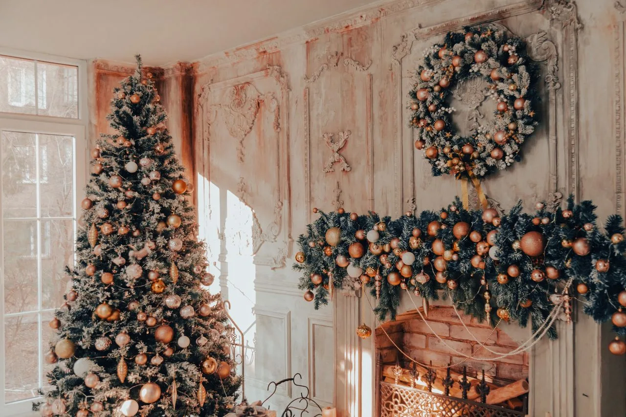 Christmas tree and wreath in front of a decorated fireplace mantel