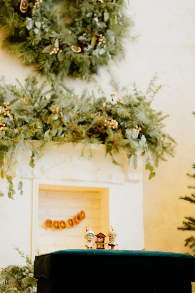 Green wreath hung above a lush pine and eucalyptus garland on a white Christmas mantel