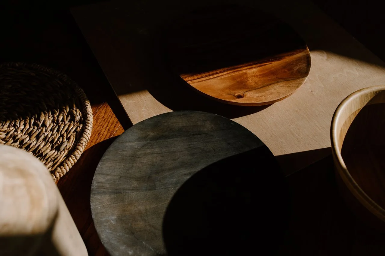 Handmade wooden bowls casting soft shadows on a dark table