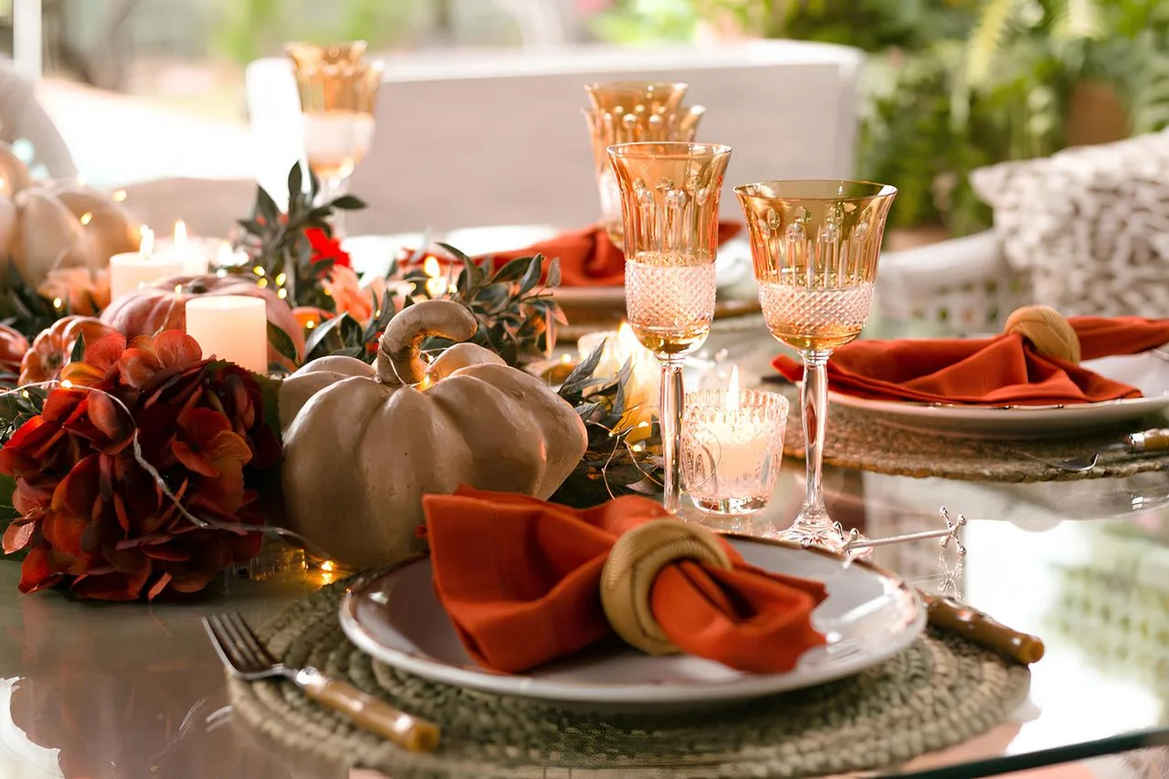 Fall dinner table with pumpkins, candles and gold-rimmed glassware
