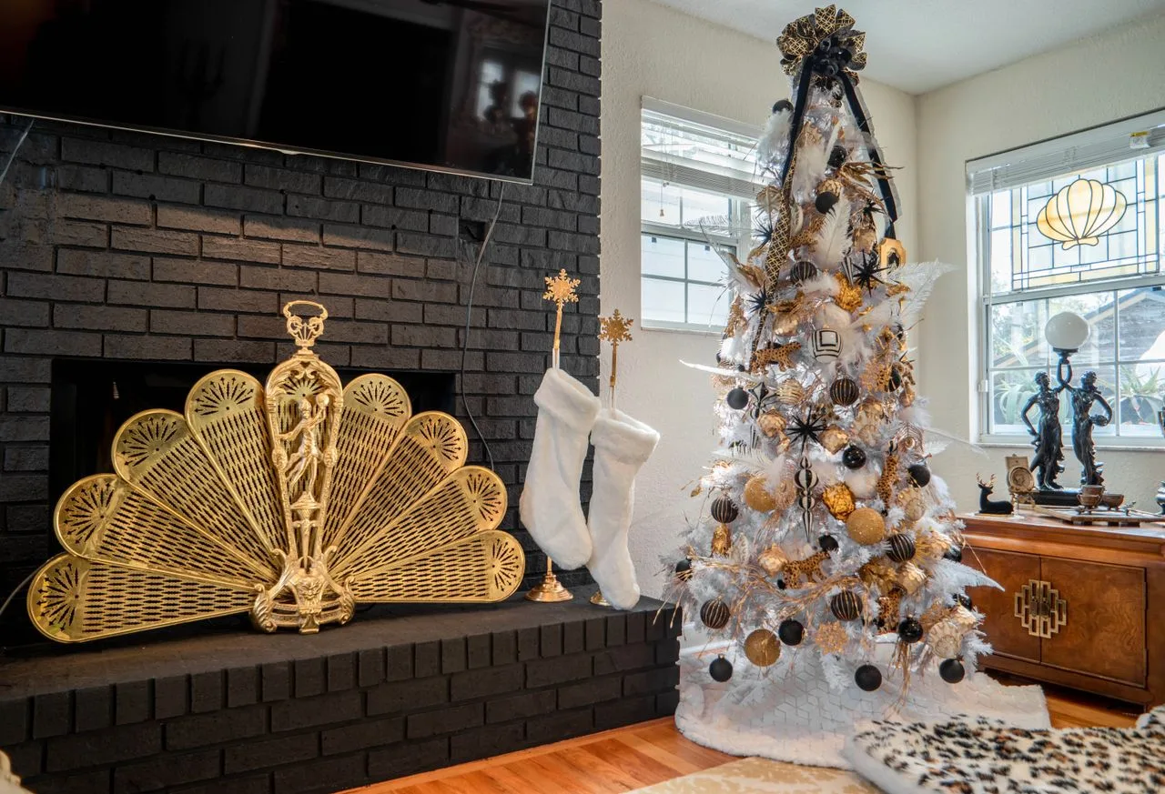 Living room corner with a white Christmas tree, gold accents and stockings